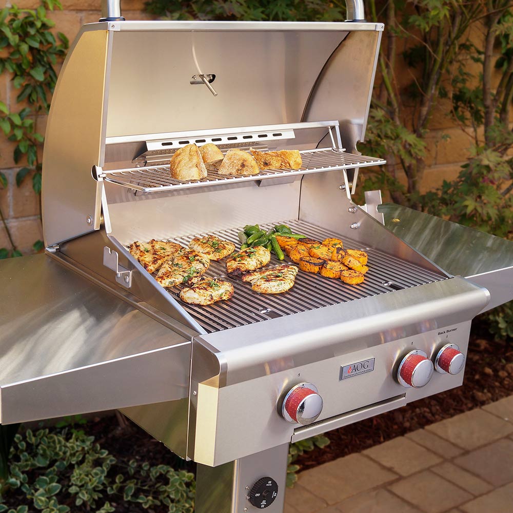 Stainless gas grill with open lid, warming rack, and food on the grates