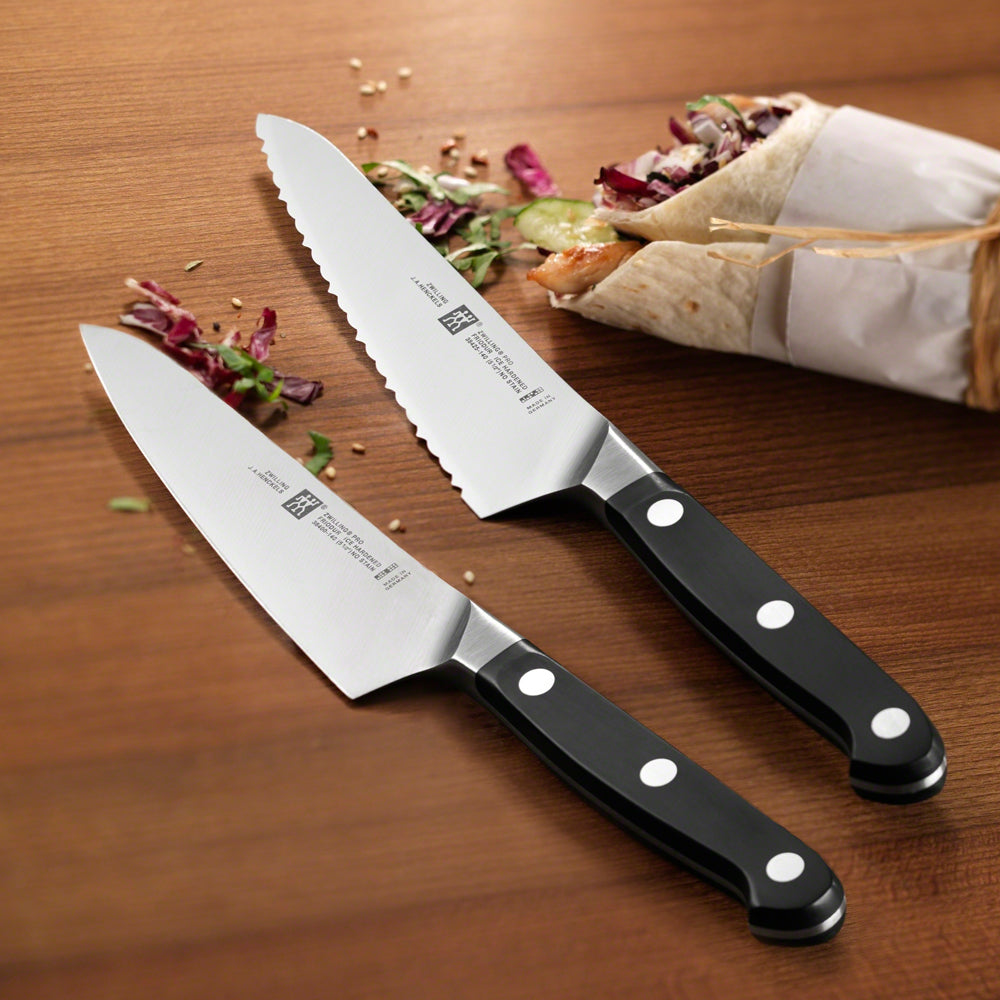 Two prep knives with curved silver blades and black handles with white rivets