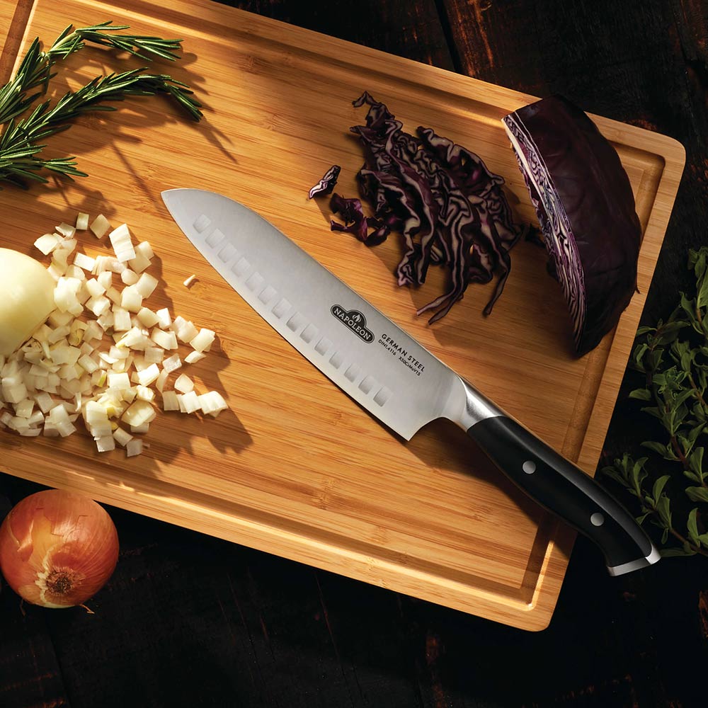 Santoku kitchen knife with black handle on a wooden cutting board