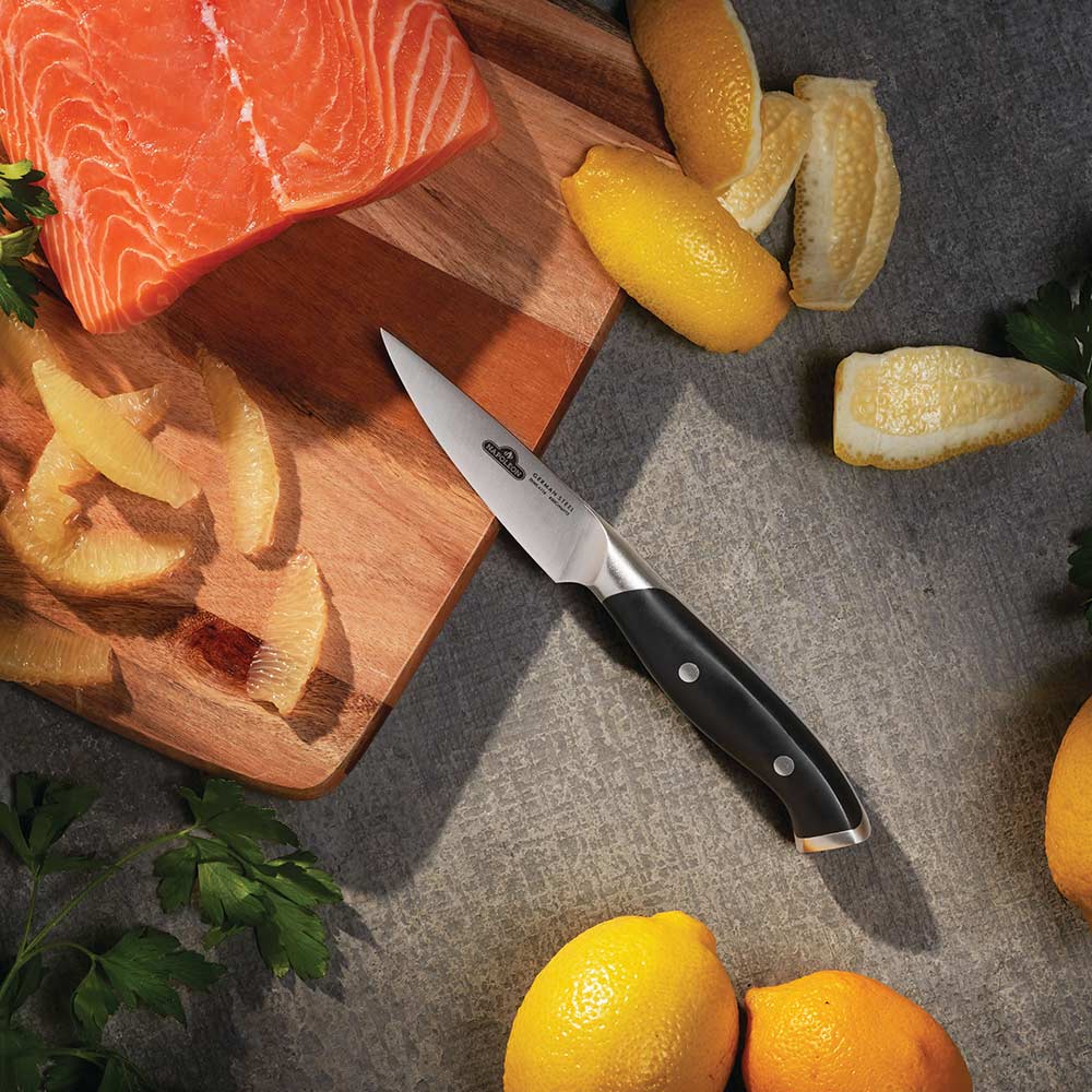 Paring knife with black handle beside citrus slices on cutting board