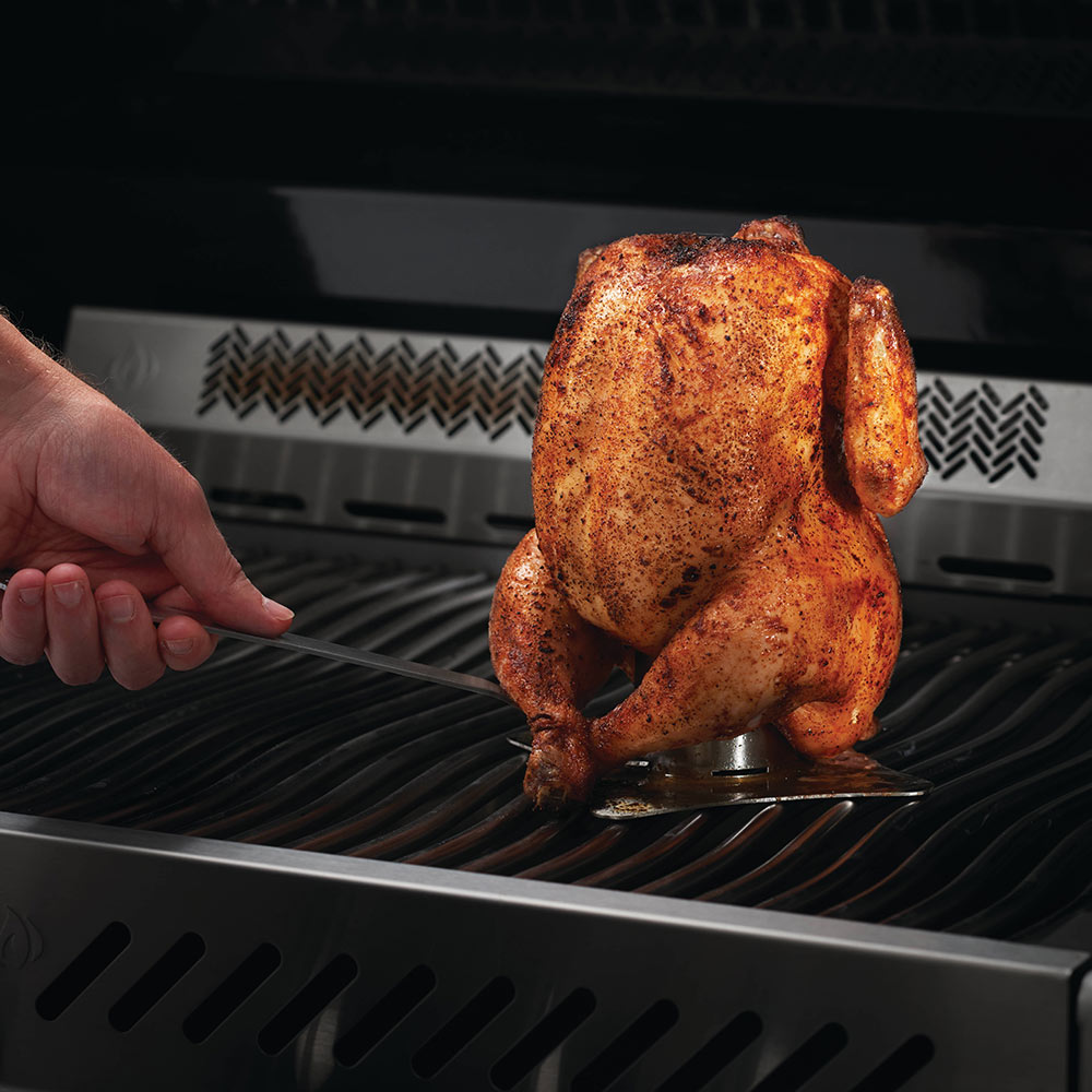 Chicken on a metal roaster stand on a grill grate