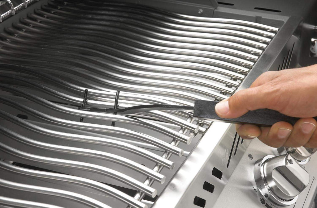 Grid lifter tool lifting a grill grate with metal prongs and handle