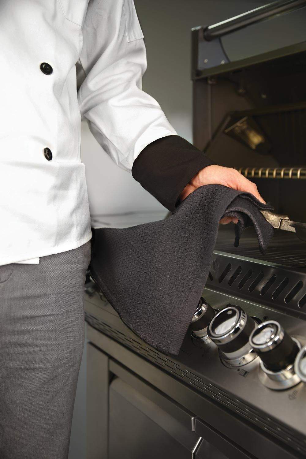 Black triangular grill towel held by a chef, with metal hanging ring