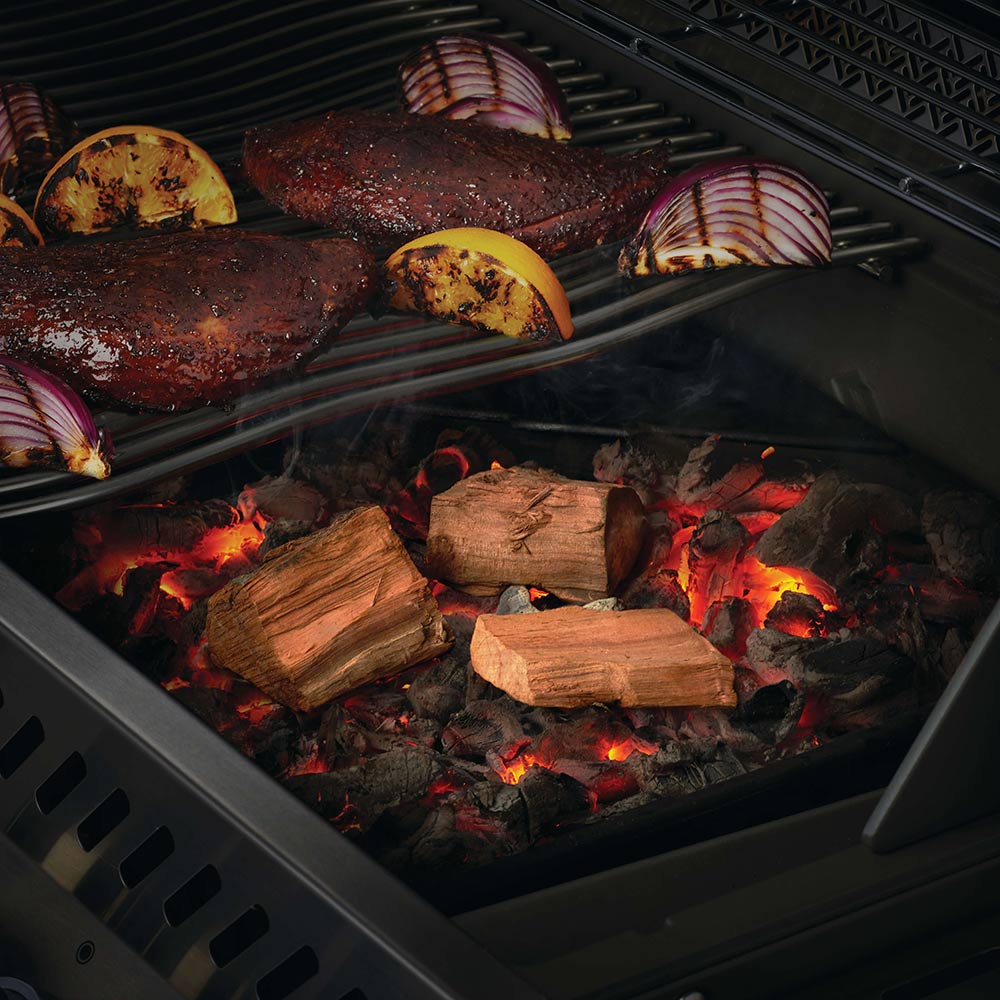 Apple wood chunks on a grill grate with glowing coals and flames