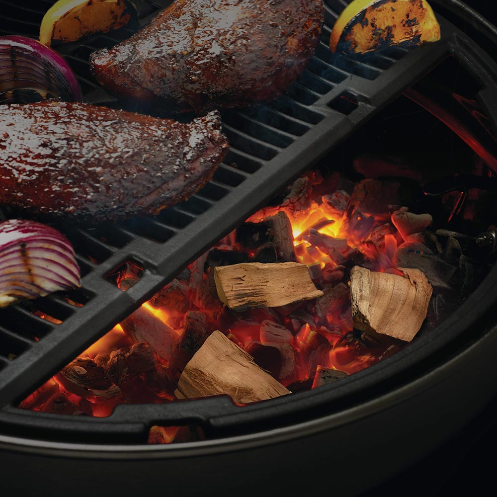 Apple wood chunks burning on grill grate with orange flames