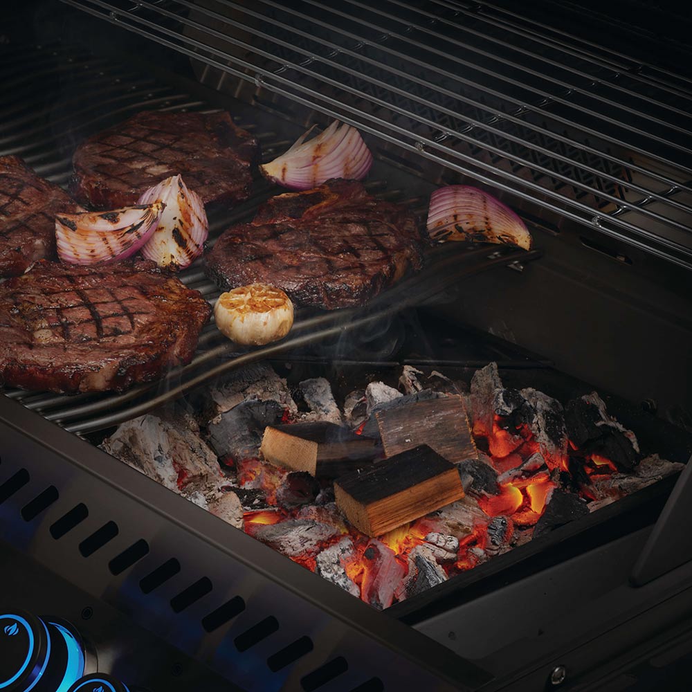 Whiskey barrel wood chunks on grill grate with orange flames