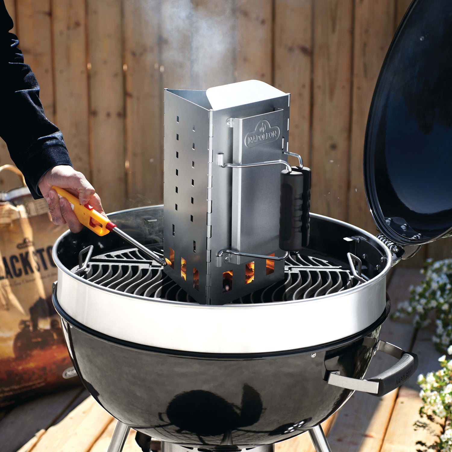 Charcoal chimney starter on grill, folded metal stack with black handle
