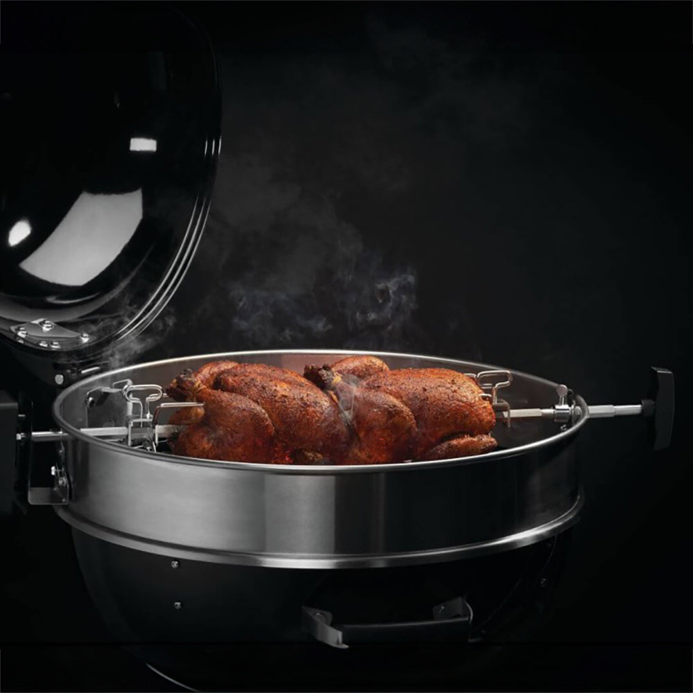 Rotisserie chicken on metal spit over grill