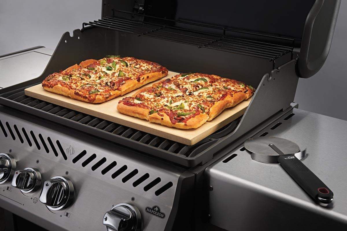 Rectangular baking stone on grill with two topped flatbreads