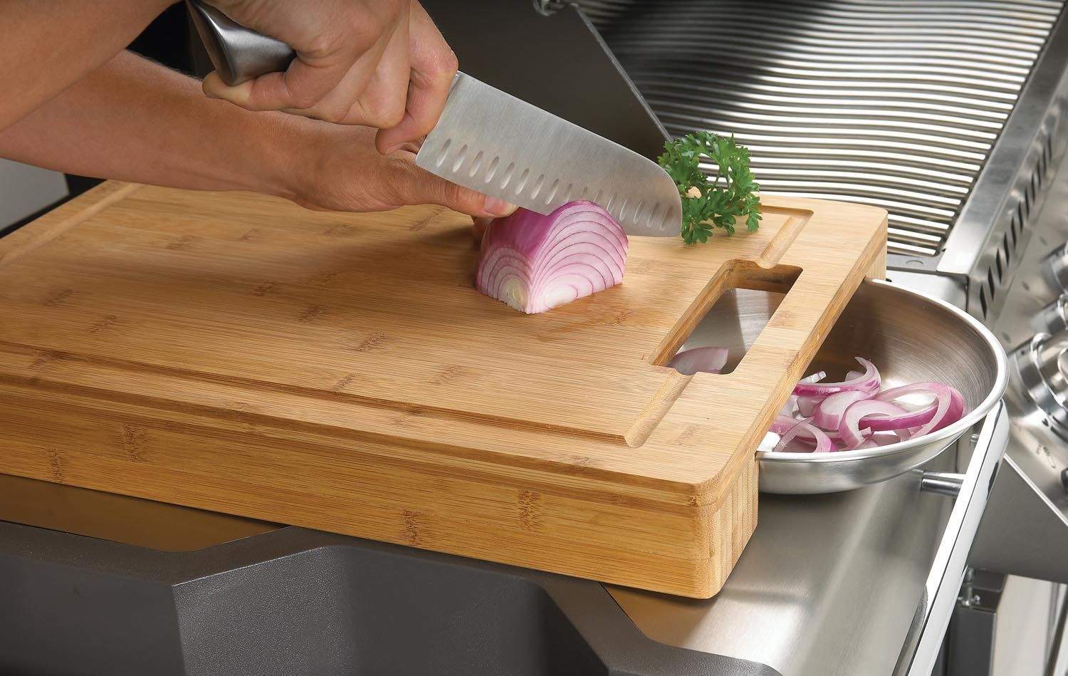 Wood cutting board with stainless bowls, knife slicing vegetables on top