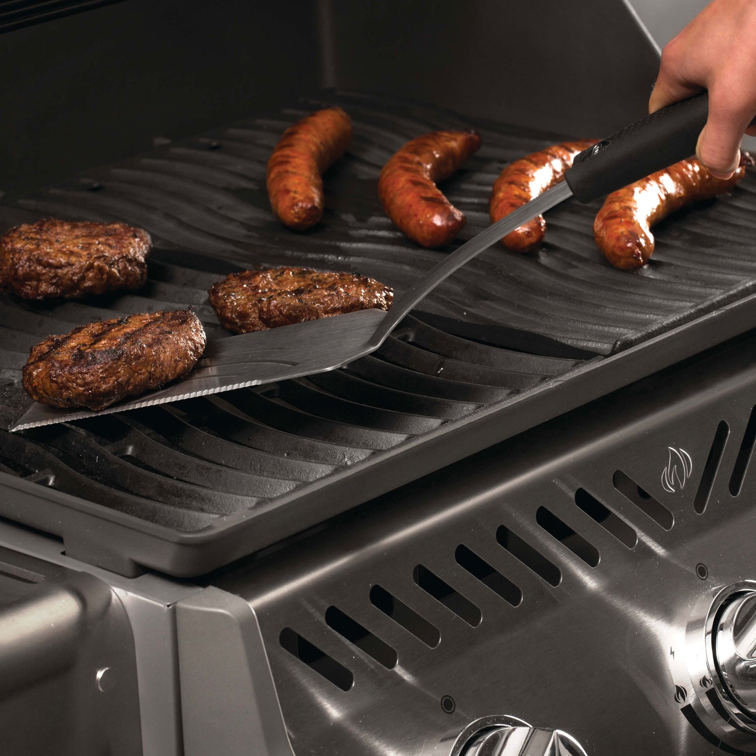 Grilling spatula with black handle and stainless blade on grill grate