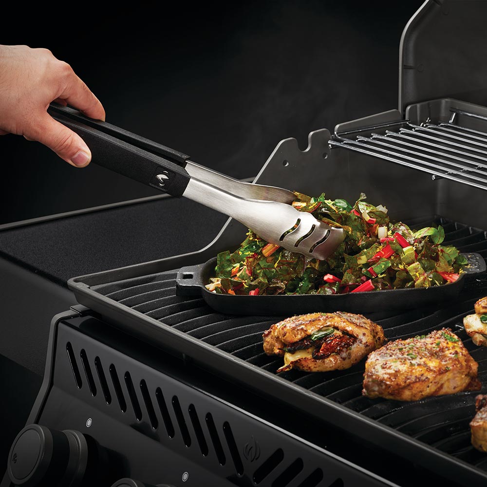 BBQ spatula with black handle and stainless blade over grilled food