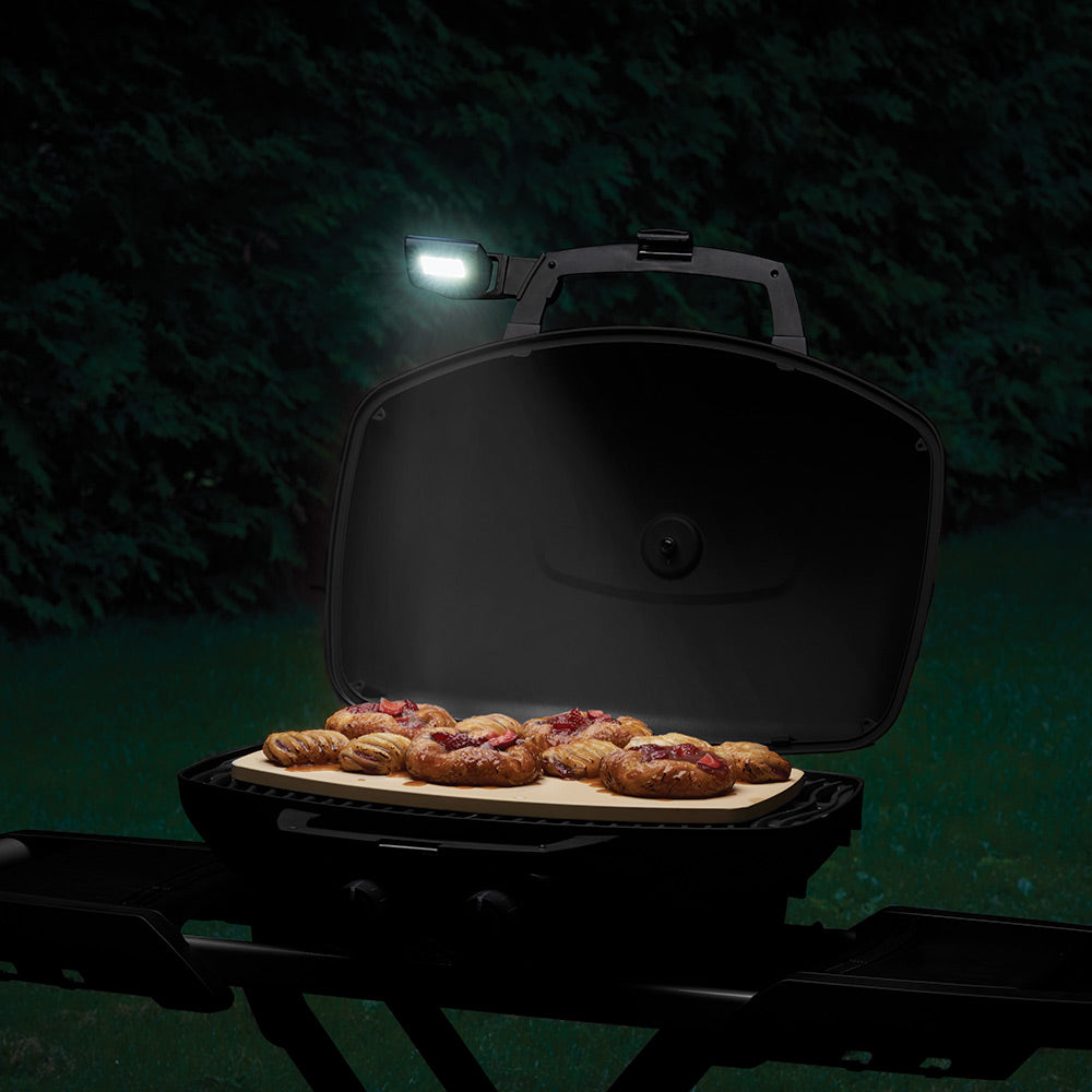 Grill lid open with glowing LED handle light above cooking surface