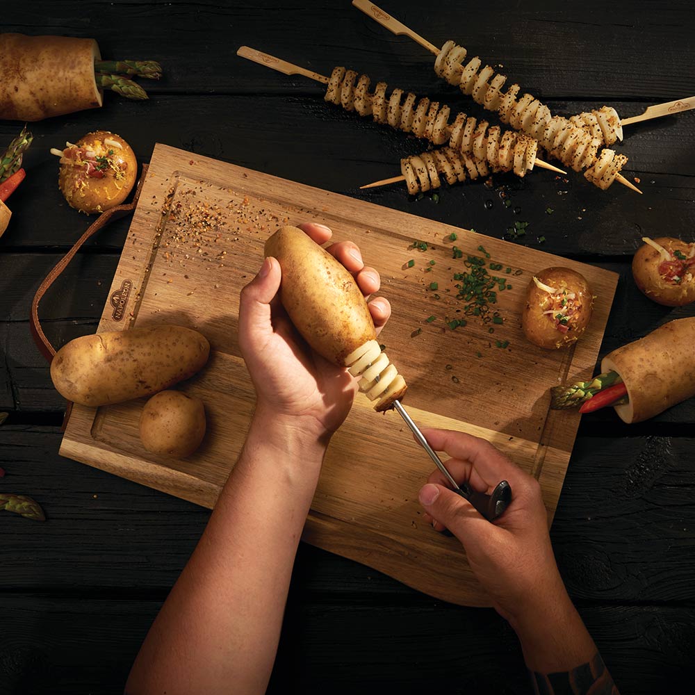 Napoleon potato spiral corer in use, hand coring a whole potato on a board