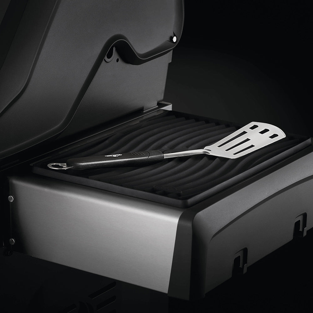 Black ribbed silicone side shelf mat on grill shelf with spatula and tongs