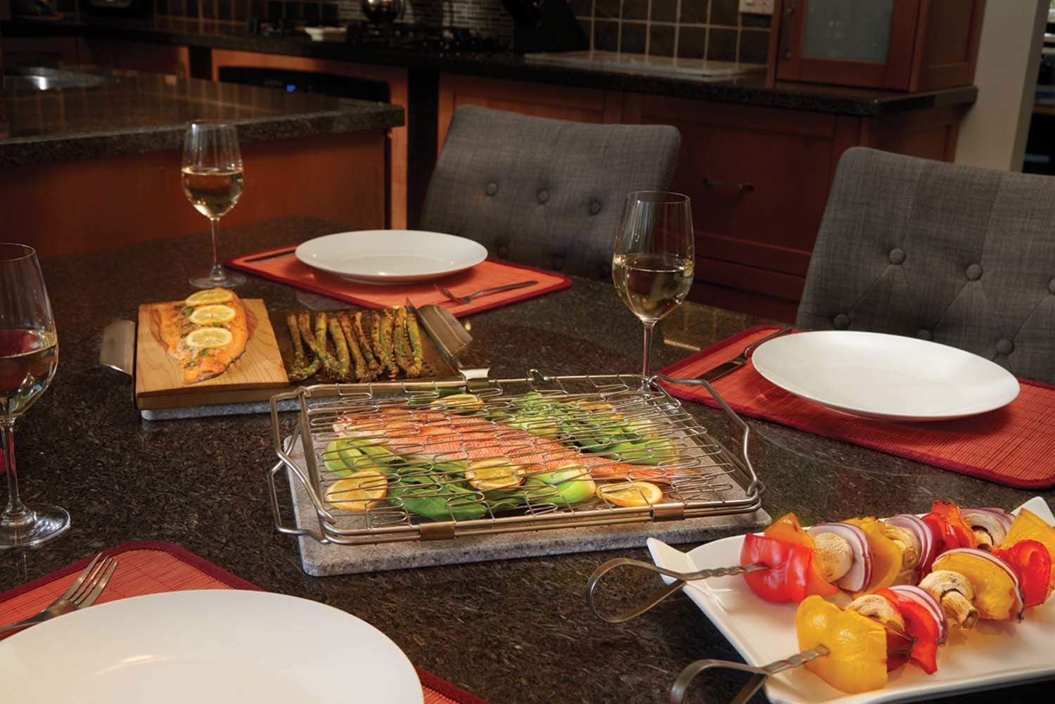 Grilling starter kit on table with metal roasting trays, skewers, and plates