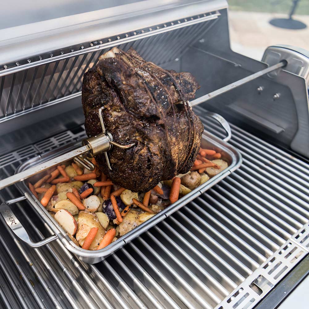 Rotisserie spit with turkey and vegetables on grill grate