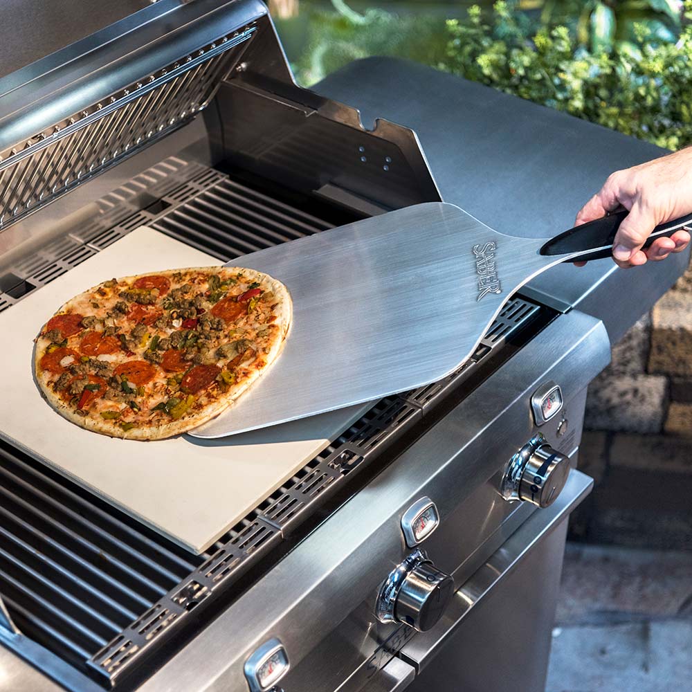 Aluminum pizza peel lifting pizza from grill
