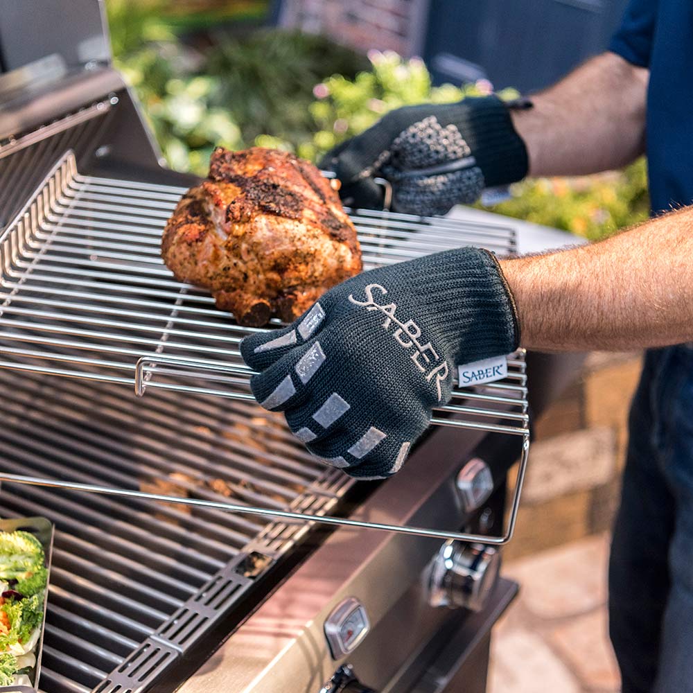 Two dark navy grill gloves on hands gripping a cooked item on the grill