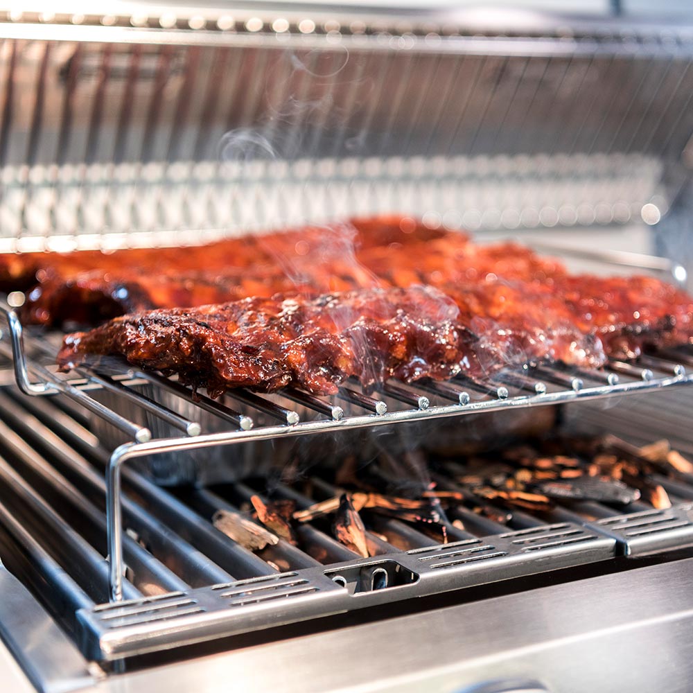 Roasting rack wire grate with browned meat pieces on grill bars