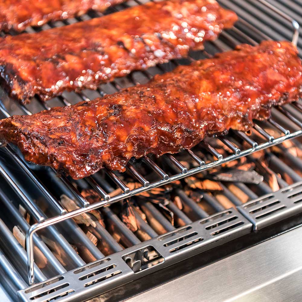 Roasting rack wire grate with multiple roasted meat pieces on grill