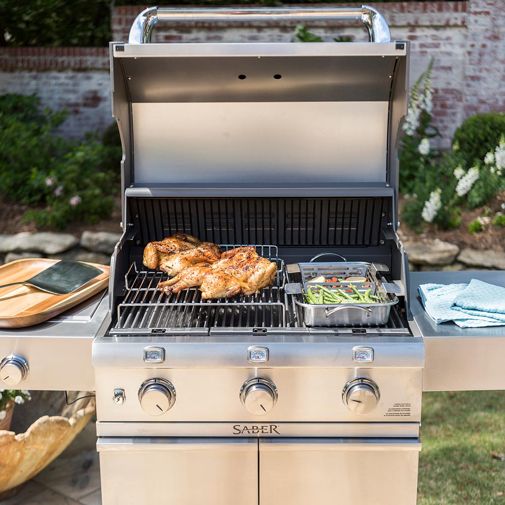 Open outdoor grill with roasting rack wire grate holding chicken and vegetables