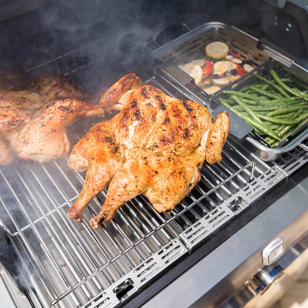Roasting rack wire grate on grill holding roasted chicken and green vegetables