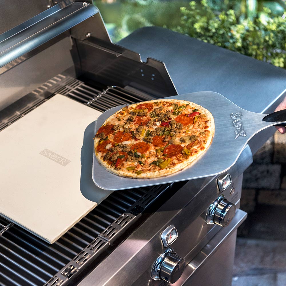 Pizza on cordierite pizza stone atop grill, light beige square