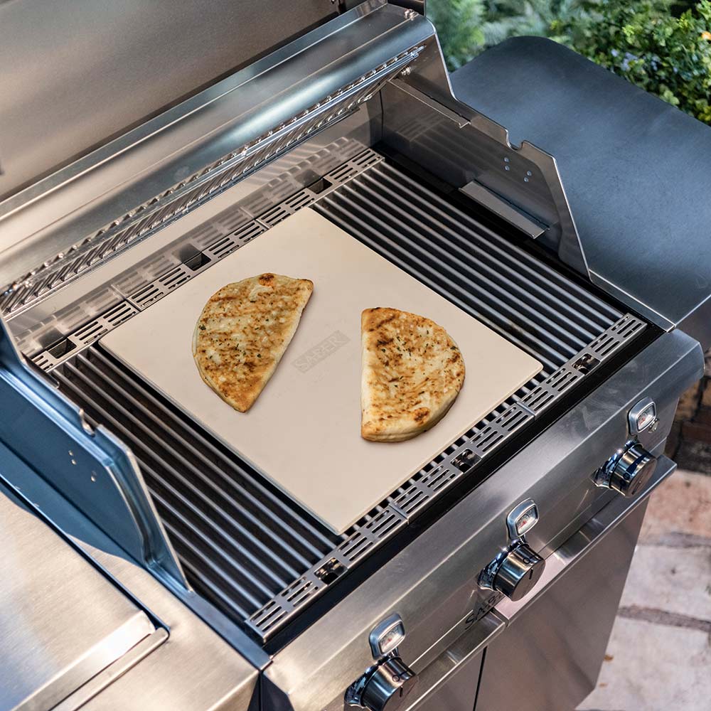 Cordierite pizza stone on grill with two pizza slices, light beige square