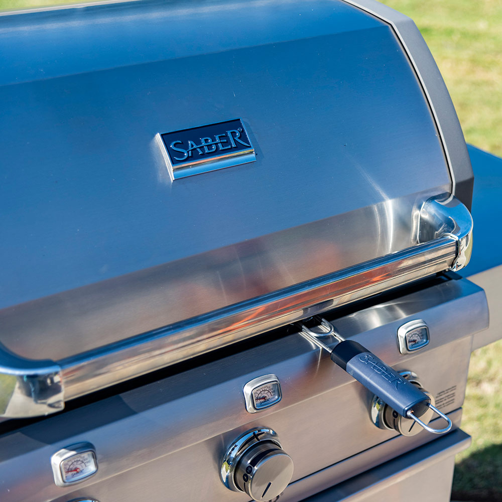 Outdoor gas grill lid with Saber logo and control knobs