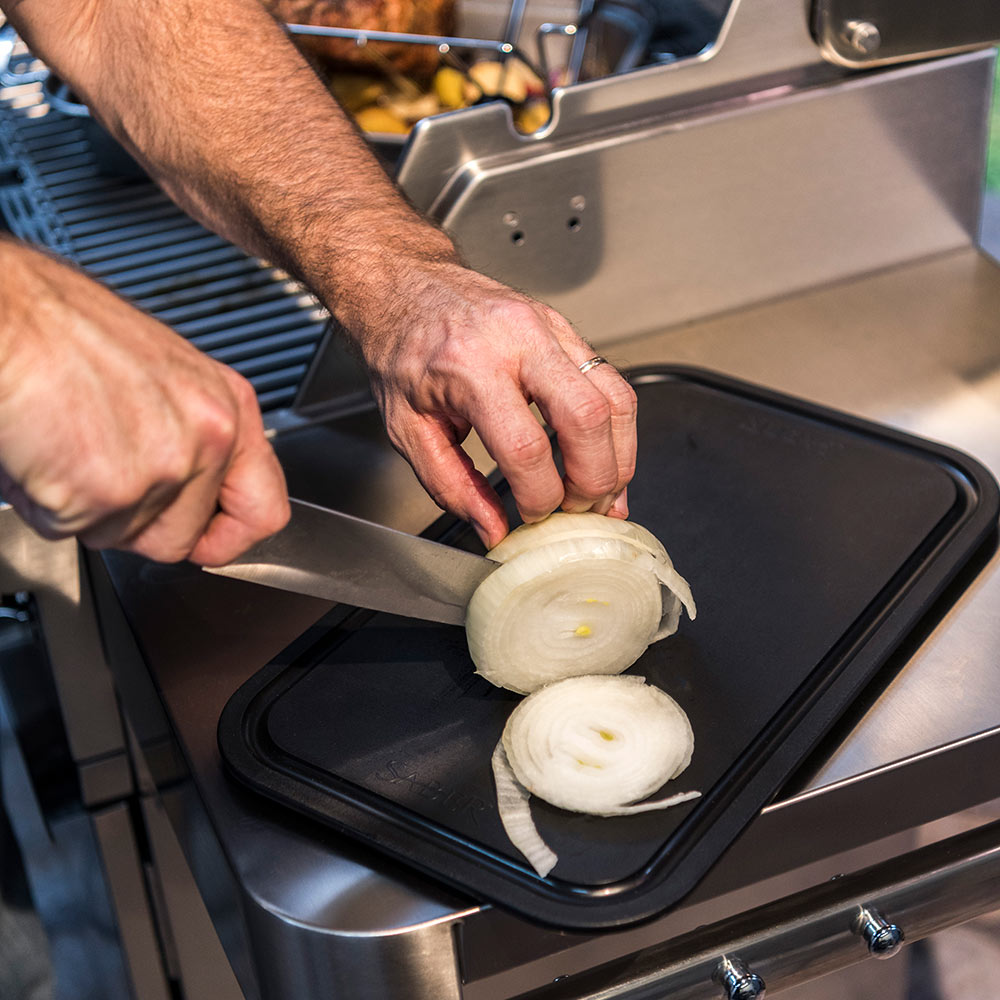 Stainless roasting pan with black cooking surface holding sliced onions