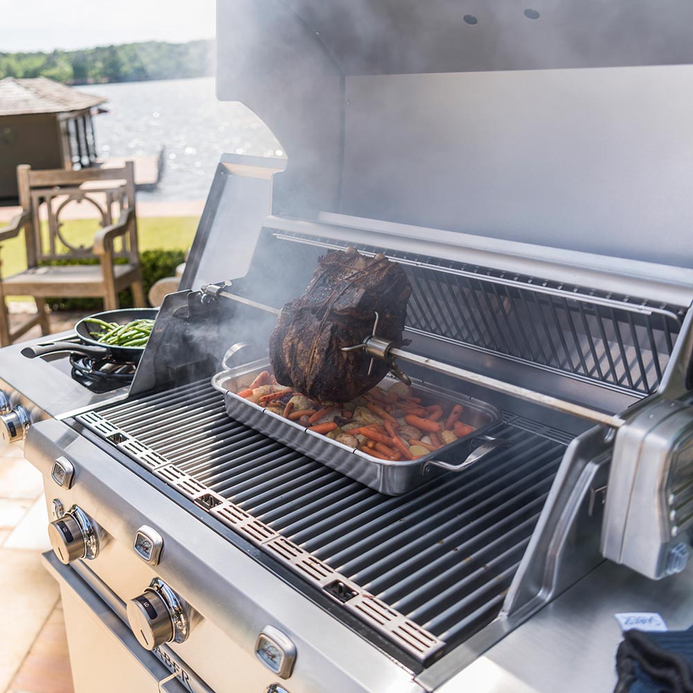 Roasting pan on grill with vegetables and a whole roast inside