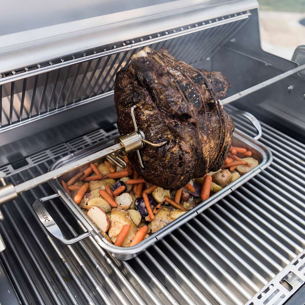 Roasting pan on grill with roast and carrots, onions, and potatoes