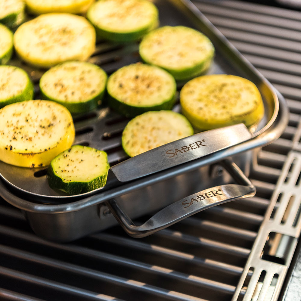 Stainless steel steamer tray on grill holding sliced zucchini