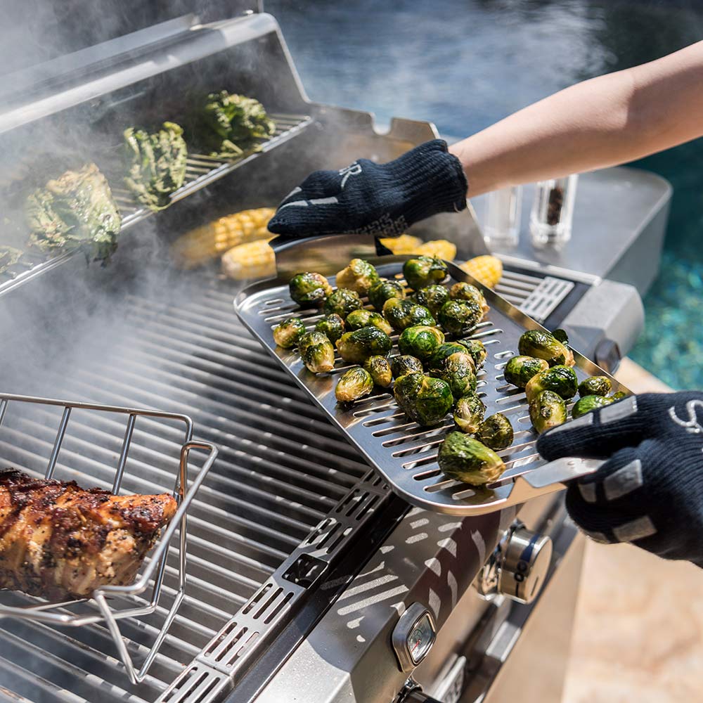 Hand lifting stainless steel steamer tray holding brussels sprouts
