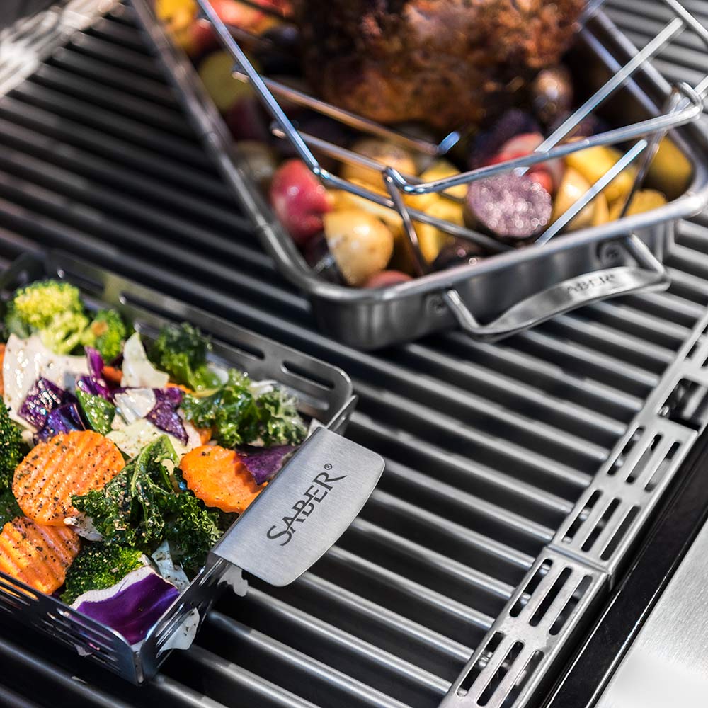 Close-up of stainless steel veggie basket with vegetables on grill grates