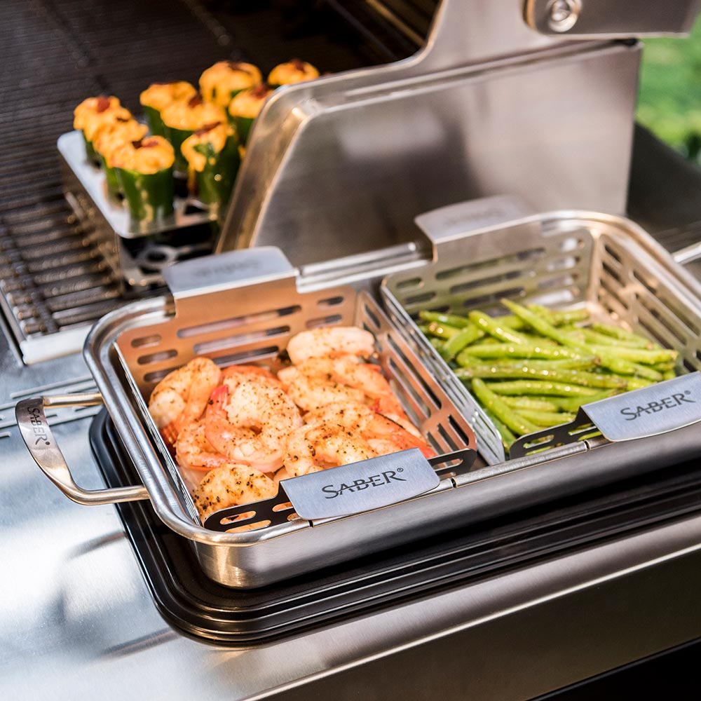 Stainless steel veggie basket set in grill holding seasoned shrimp and asparagus