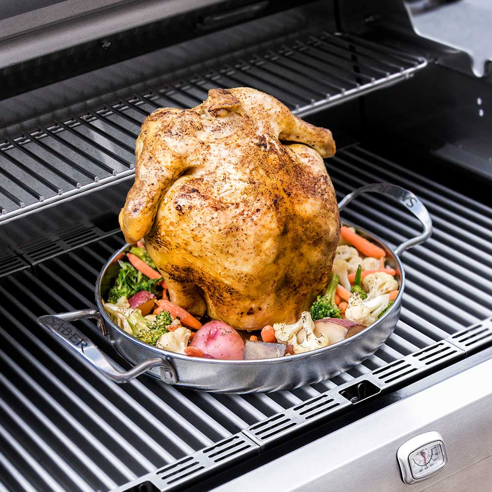 Poultry roaster holding roasted chicken with vegetables on grill grates