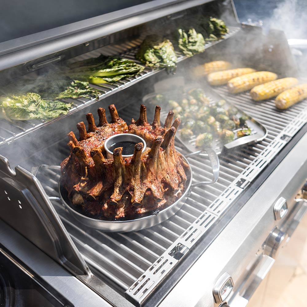 Stainless steel roaster basket with seasoned meat rack on grill
