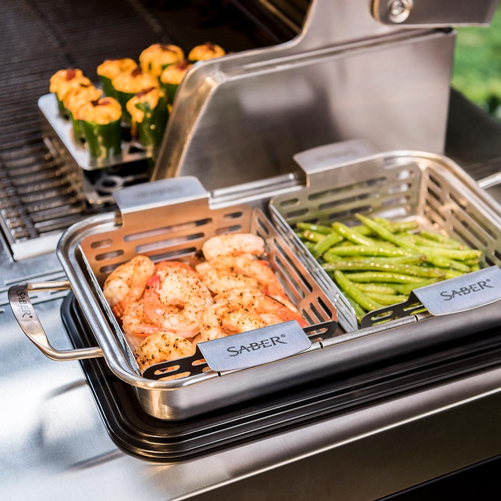 Stainless roasting trays with shrimp and asparagus on a grill