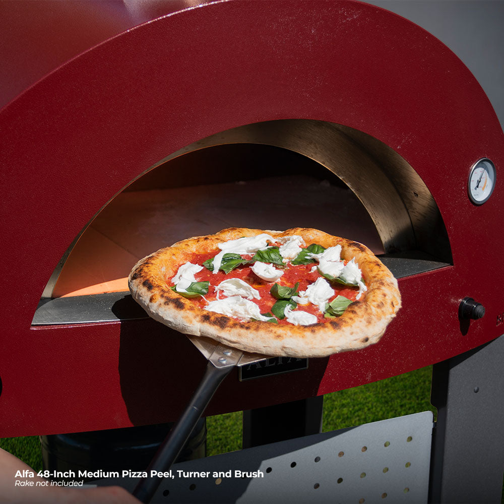 Alfa pizza peel holding a topped pizza at a small outdoor oven opening
