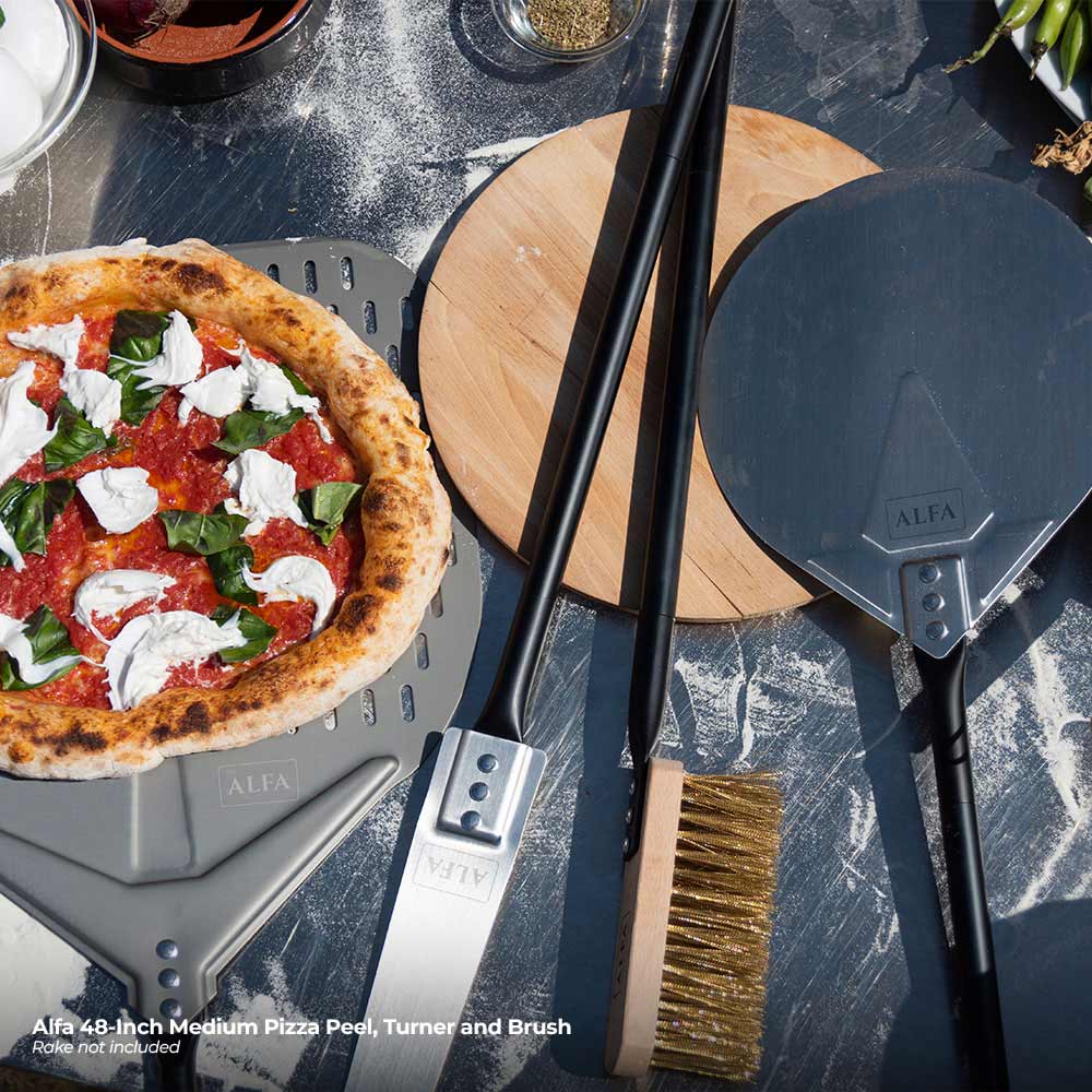 Alfa pizza peel and brush beside a topped pizza on a perforated board
