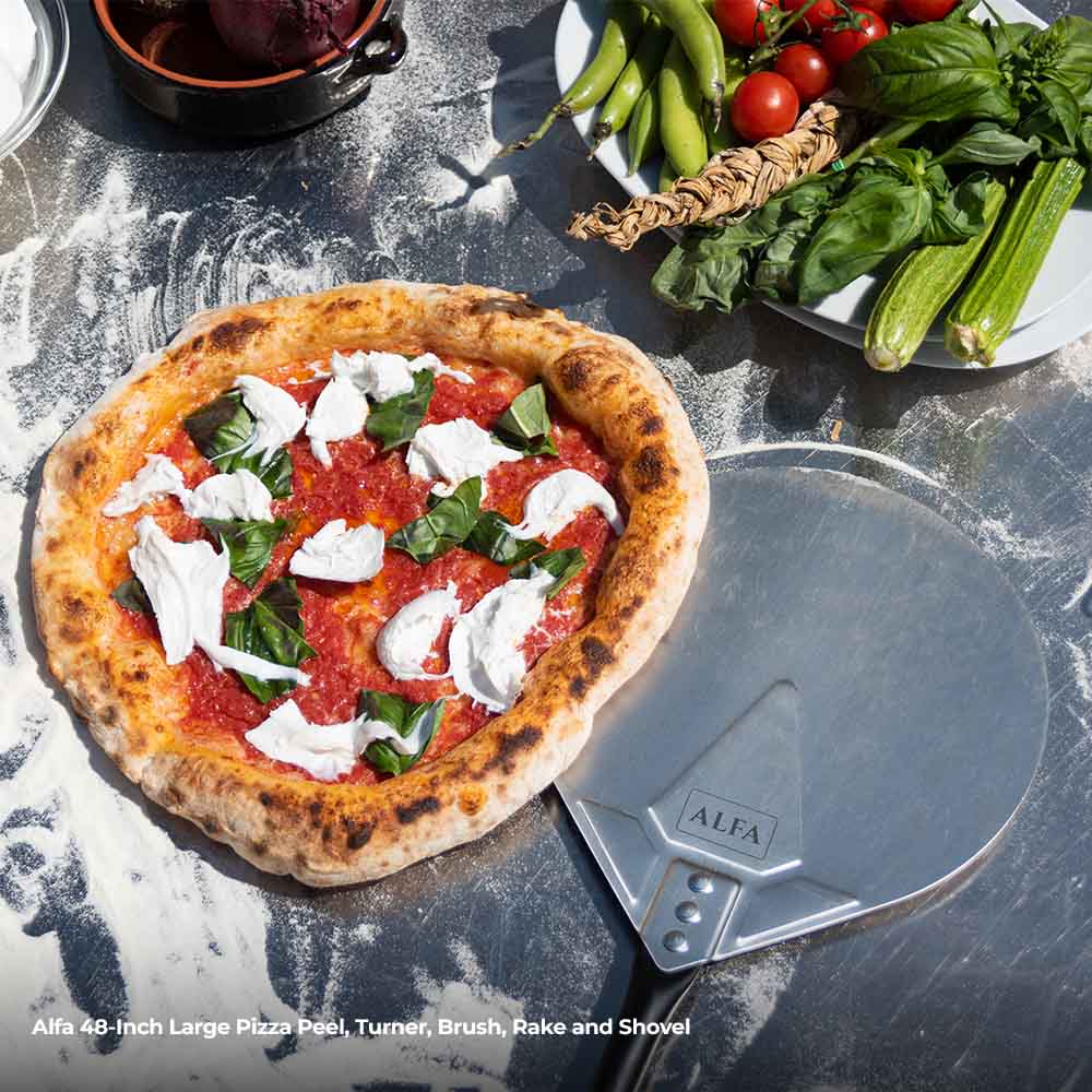 Large pizza peel and round turner with black handles beside topped pizza
