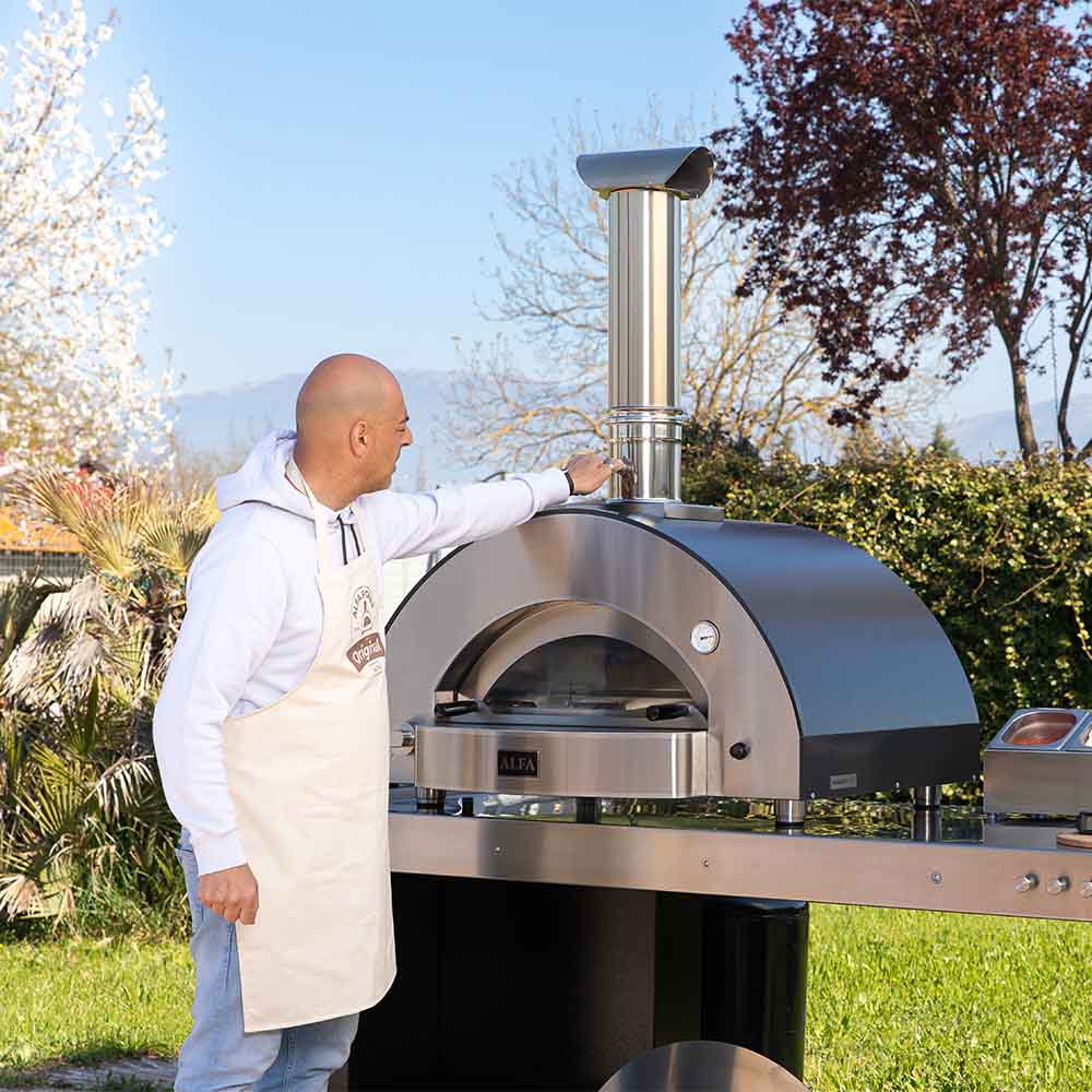 Person adjusting the stainless steel chimney stack on an outdoor pizza oven
