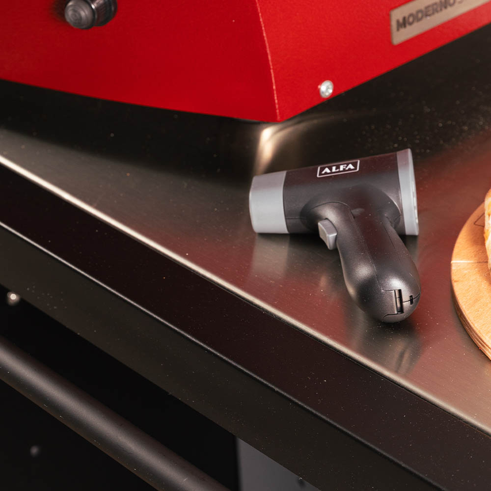 Laser thermometer with handle and front head, placed on equipment surface
