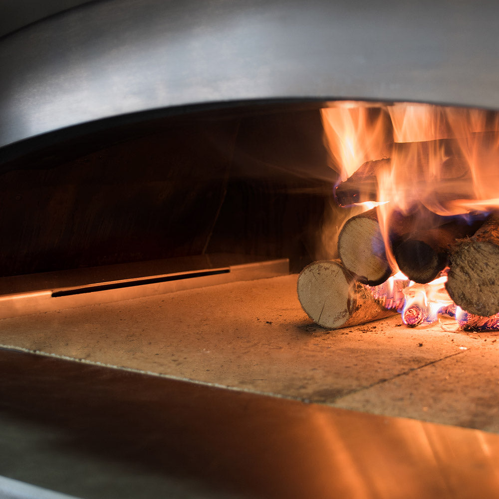 Pizza oven interior with flames, stone floor, and metal bar