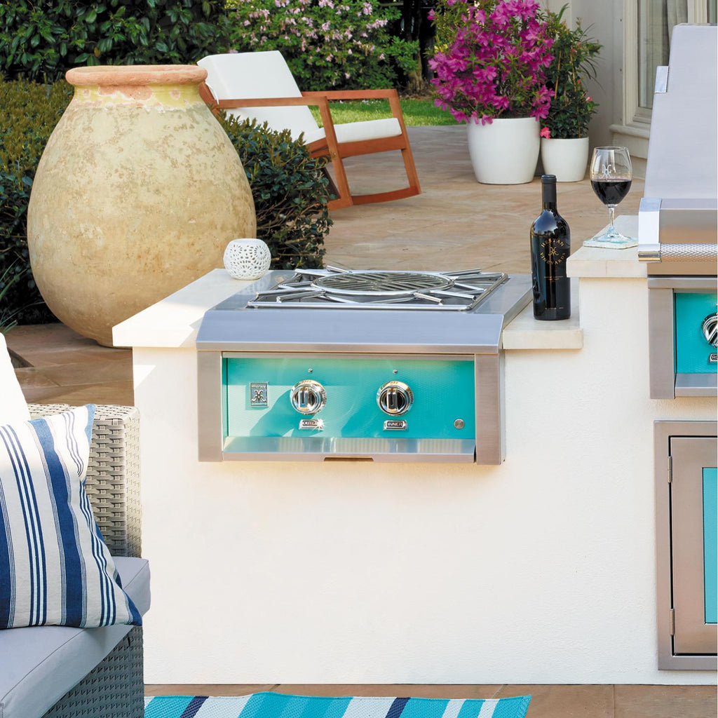 Hestan built-in power burner with teal front panel, two dial controls, and stainless grates