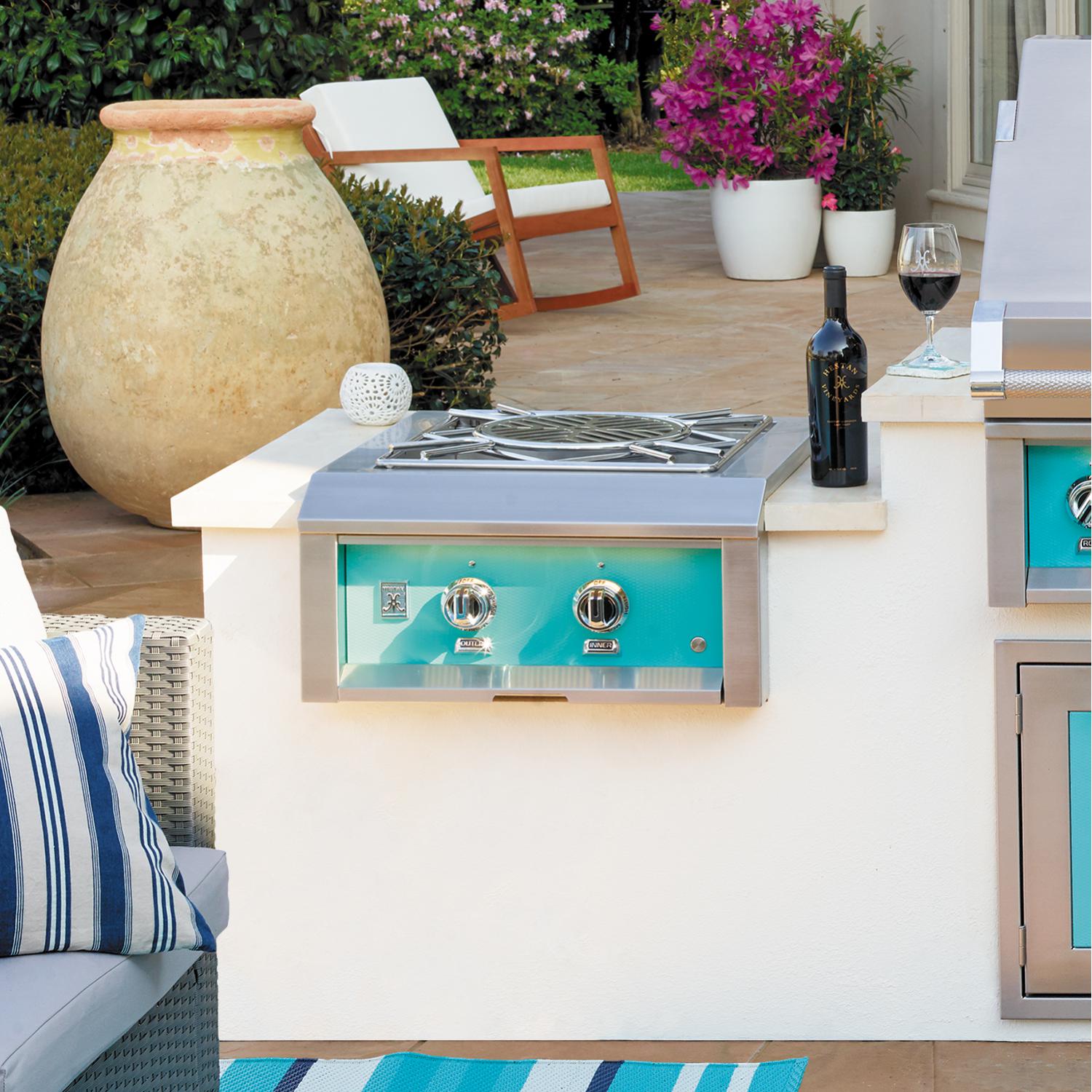 Hestan built-in power burner with teal front panel, two dial controls, and stainless grates