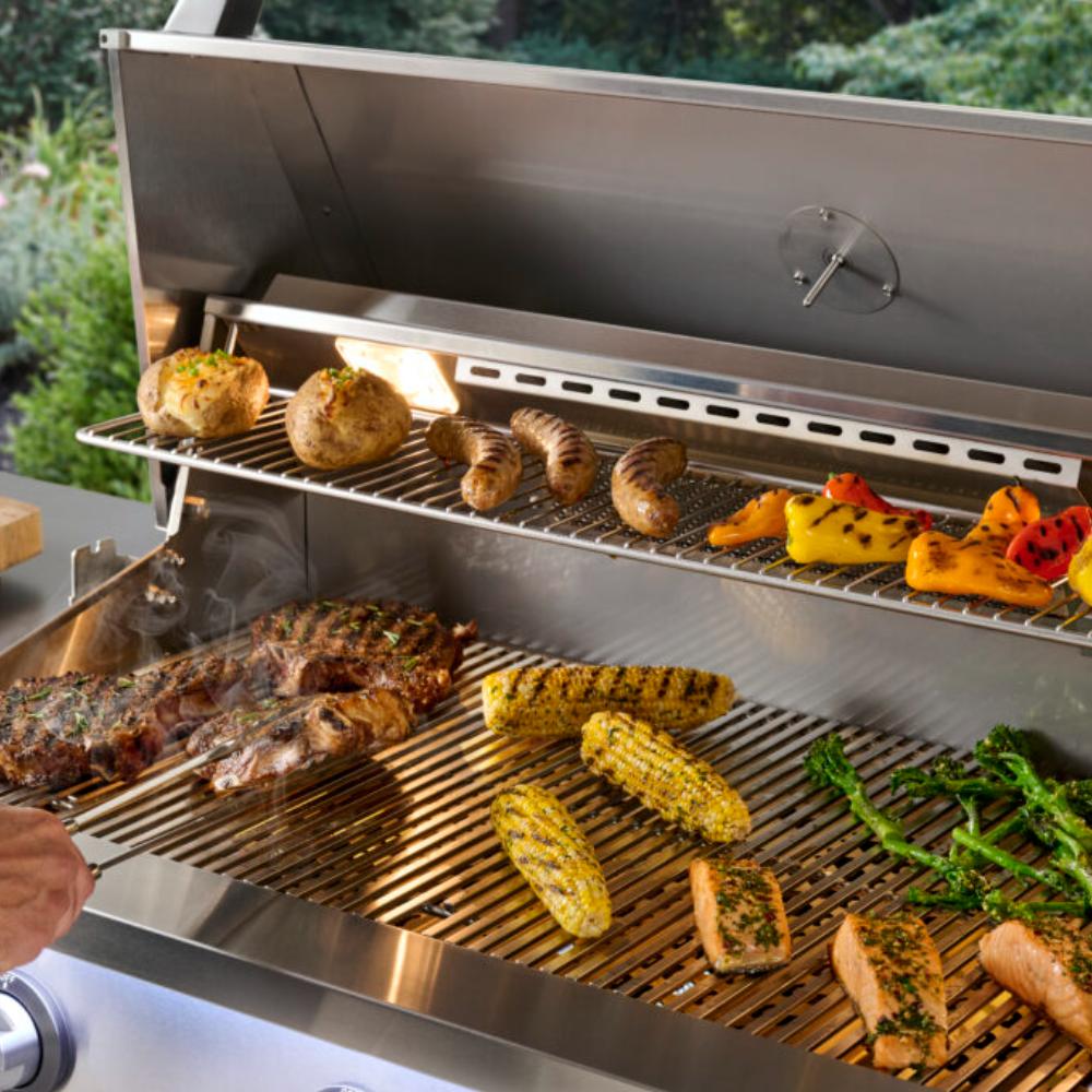 Open built-in gas grill with browned meats and corn on the cooking grates