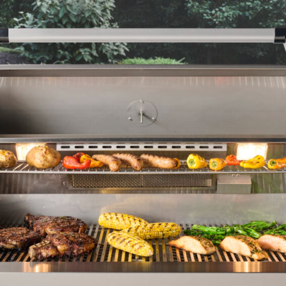 Open built-in gas grill with metal grates, burners, and assorted vegetables and sausage